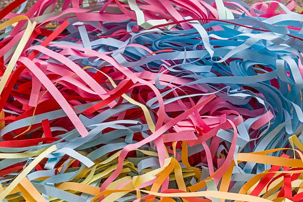 Many colorful paper chips crushed by a shredder