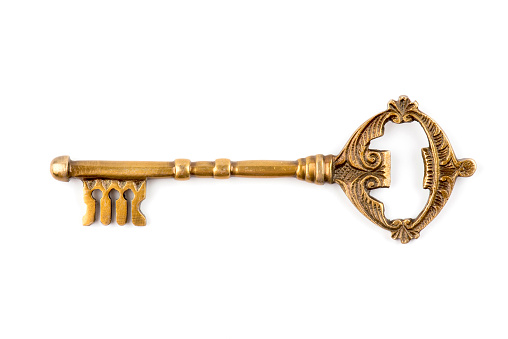 An old and mystic key that is rather large in size isolated on white background.