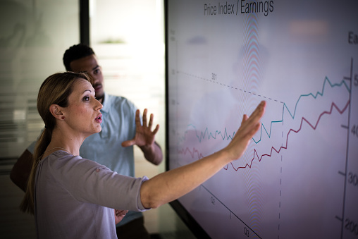 Businesswoman explaining graph to his coworker in conference room.