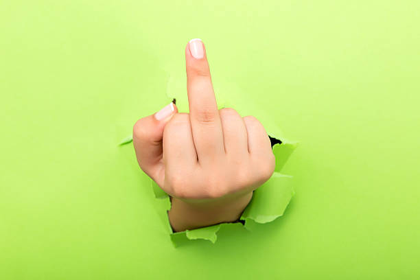 Human hand gesturing with middle finger through the paper hole isolated on white background