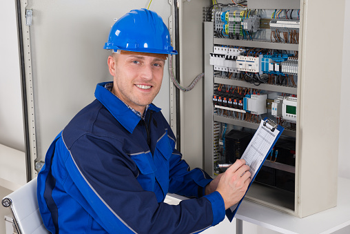 Young Male Technician Holding Clipboard While Examining Fusebox