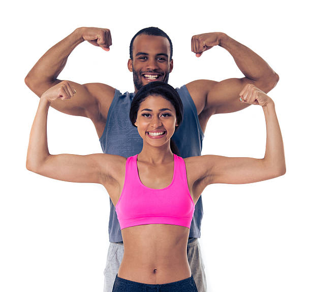 Beautiful Afro American couple in sports clothes is showing muscles, looking at camera and smiling, standing one by one, isolated on white background