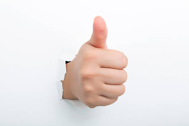 istock Thumbs up through the paper hole isolated on white background 598525130