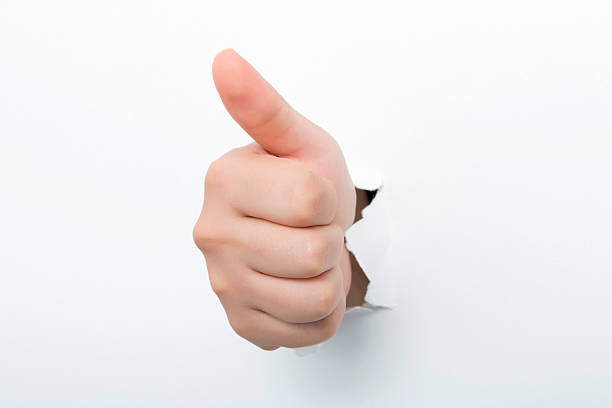 istock Thumbs up through the paper hole isolated on white background 598525284
