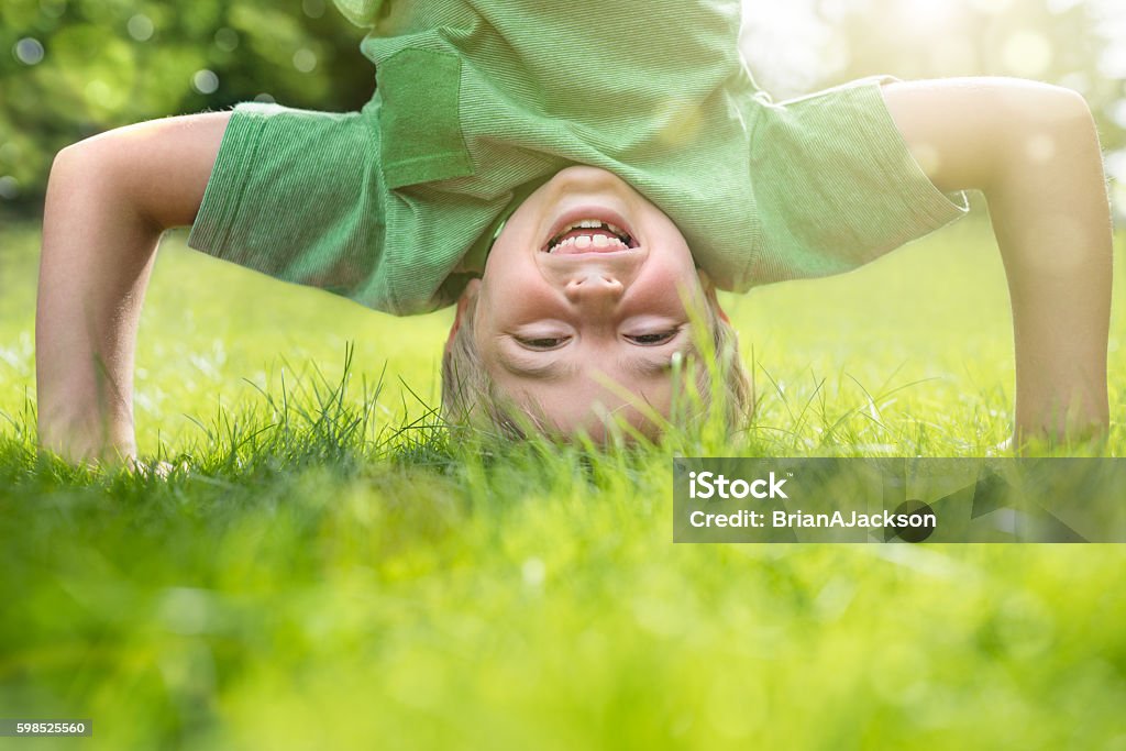 Young boy doing a headstand on the grass Young boy doing a headstand on the grass in the summer sunshine Child Stock Photo