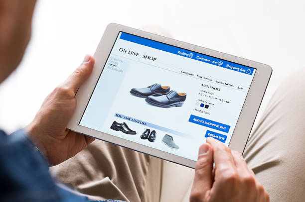 Man shopping online Young man looking at shoes online. Man looking at various shoes options over internet through digital tablet. Casual man makes online shopping at home with digital tablet. shoe store stock pictures, royalty-free photos & images