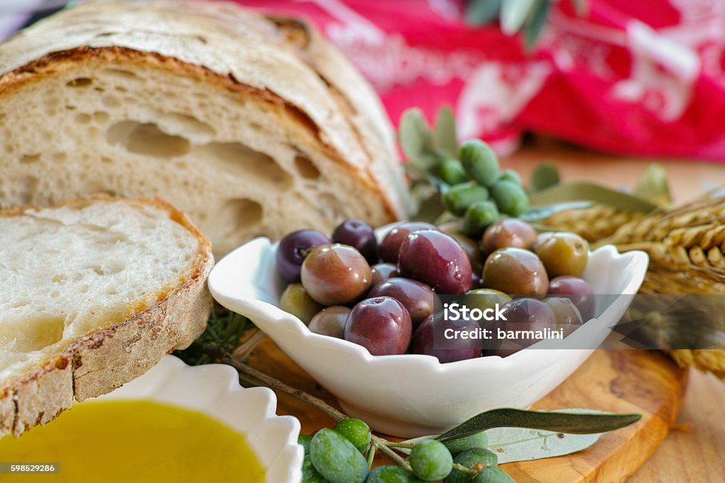 Traditional italian appetizer - fresh homemade bread, extra virg Traditional italian appetizer - fresh homemade bread, extra virgin olive oil and olives on wooden background Appetizer Stock Photo