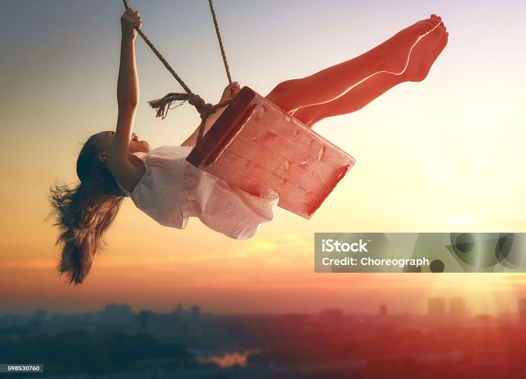 child girl on swing Happy laughing child girl on swing in sunset summer Using A Swing Stock Photo