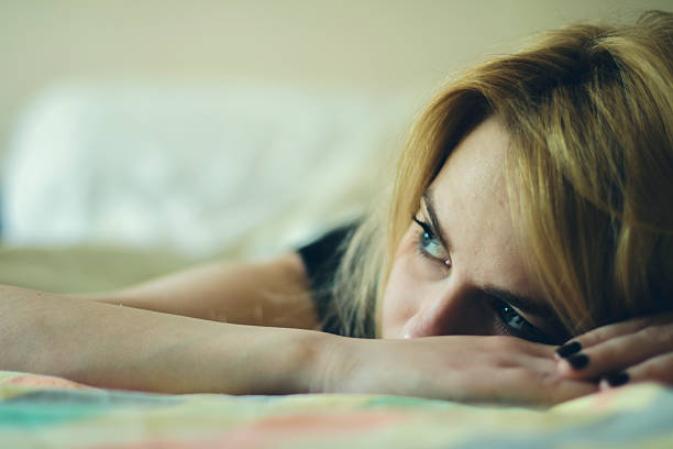 beautiful woman laying down in a bed - women moving up looking human hair imagens e fotografias de stock