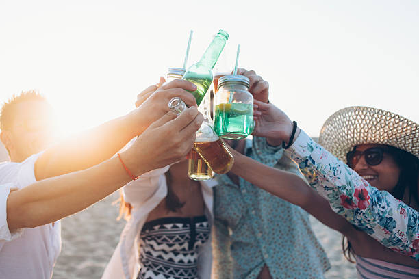istock Smiling friends drinking beer on the beach and cheering 598531746