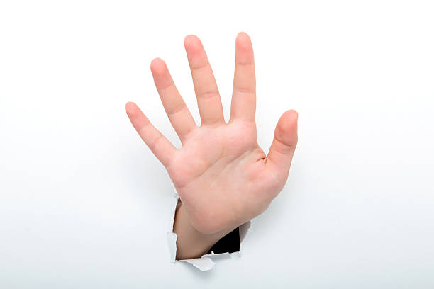 istock Female hand reaching through torn white paper sheet 598532776
