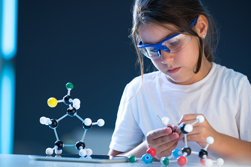 Young scientist looking at a molecular structure model.