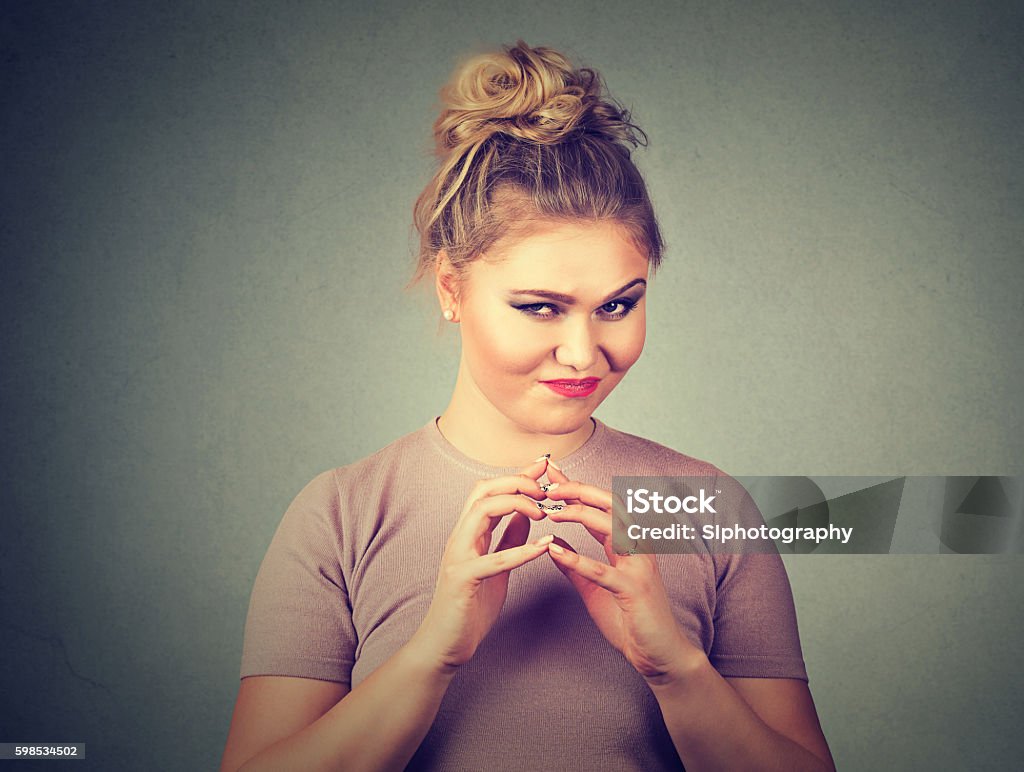 Sneaky, sly, scheming woman plotting something Closeup portrait of sneaky, sly, scheming young woman plotting something isolated on gray background. Negative human emotions, facial expressions, feelings, attitude Conspiracy Stock Photo