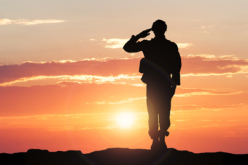 Soldado saludando durante la puesta de sol photo