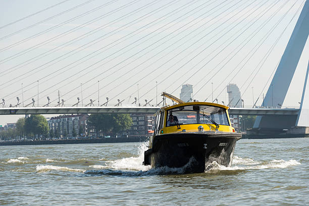 watertaxi on the rotterdam river Maas Rotterdam, Netherlands - August 31, 2016: Watertaxi in the city of Rotterdam with the erasmus bridge as background ,this is the biggest port in Holland and also one of the biggest in the world watertaxi stock pictures, royalty-free photos & images