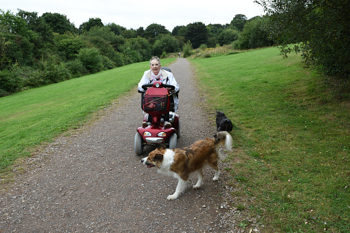 Senior woman with electric scooter out with her dogs