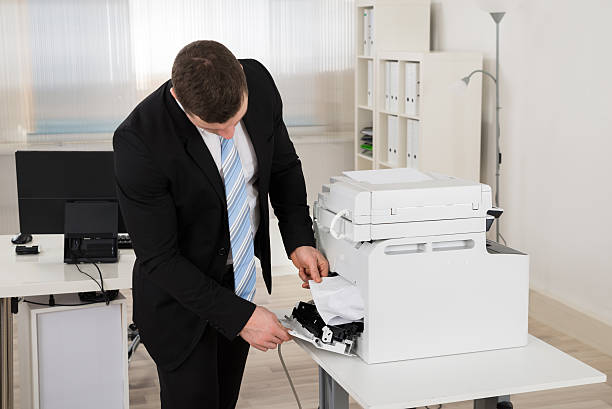 istock Businessman Removing Paper Stuck In Printer 598540998