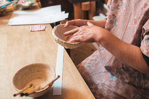 istock Craftsperson adding strips of paper to a handmade bowl 598541202