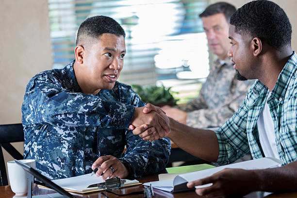 Asian soldier meeting with young man at military recruitment event Mature adult Asian soldier is smiling while working in military recruitment office during recruitment event. He is talking to young adult about joining the armed forces. us navy photos stock pictures, royalty-free photos & images