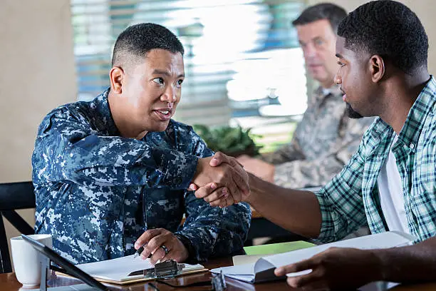 Photo of Asian soldier meeting with young man at military recruitment event