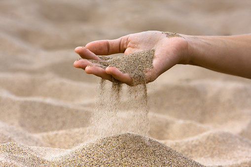 sand running through hand of woman on the beach