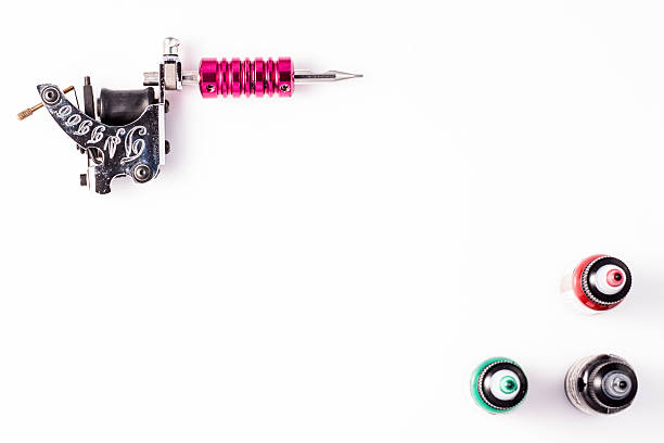 pistola de tatuajes y tres botellas de tinta - tattoo gun fotografías e imágenes de stock