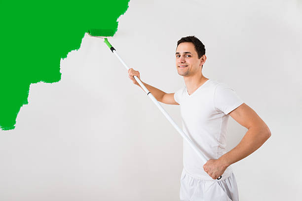 istock Man Painting Wall With Green Paint Roller 598545982