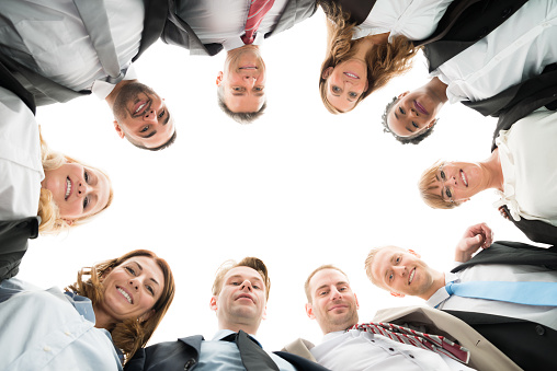 Directly below portrait of confident business team standing in huddle against white background