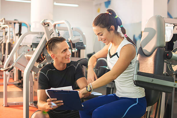 istock Young woman with personal trainer at gym. 598549636
