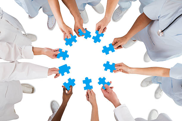 istock Medical Team Holding Blue Jigsaw Pieces In Huddle 598550066