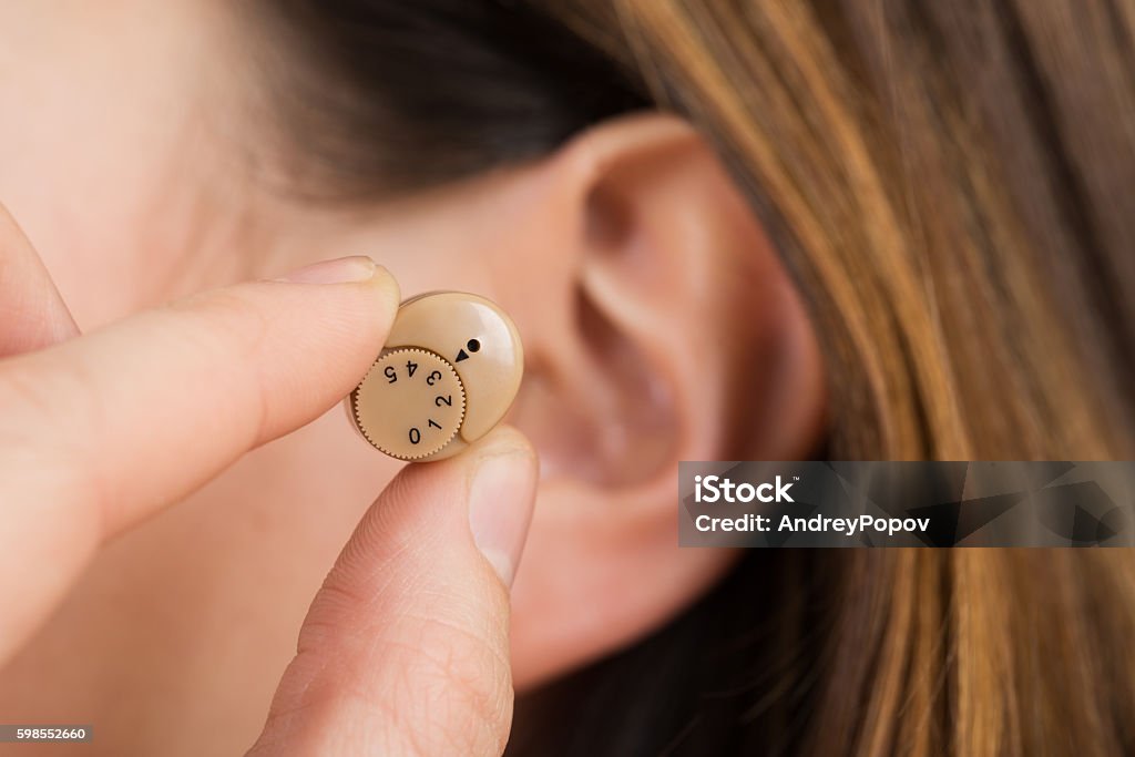 Woman Hands Putting Hearing Aid In Ear Close-up Of A Woman Hands Putting Hearing Aid In Ear Hearing Aid Stock Photo