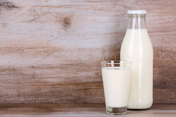 istock Milk in a glass and bottle on wooden background. 598553466