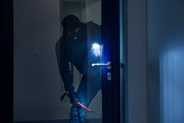 Thief With Flashlight Trying To Break Door Thief with flashlight trying to break glass door with crowbar burglar stock pictures, royalty-free photos & images