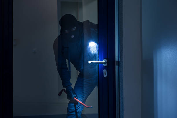 thief with flashlight trying to break door - burglary imagens e fotografias de stock