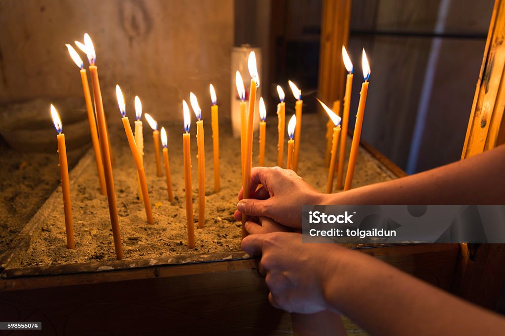 Mother and child lighting a candle in Orthodox Church Mother and child lighting and holding a candle in Orthodox Church Candle Stock Photo