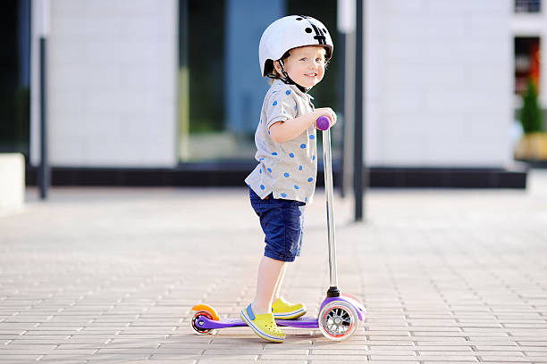 istock Toddler boy learning to ride scooter 598556216