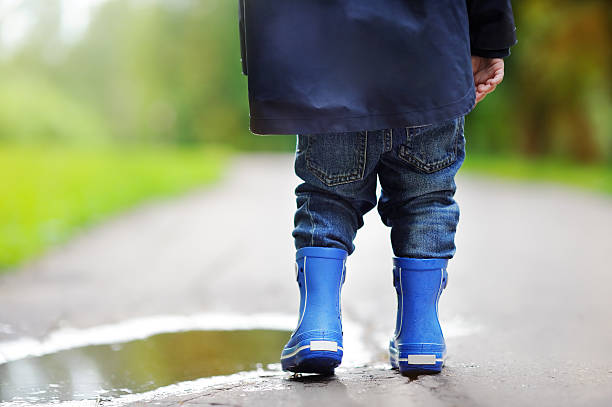 istock Toddler wearing rain boots standing near a puddle 598557174