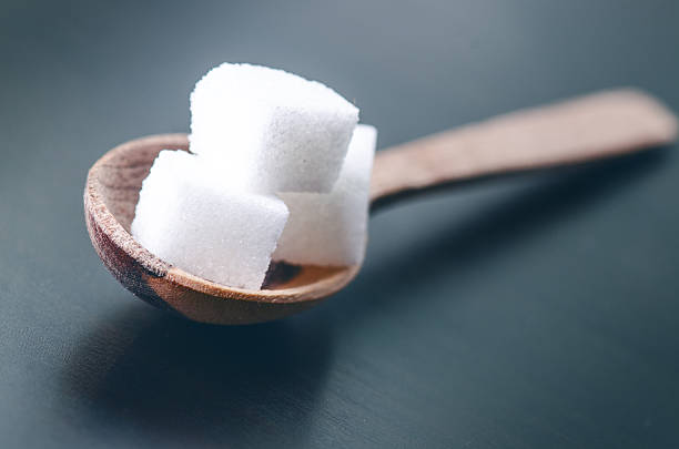 istock Cubes of sugar on a wooden spoon. Dark blue background 598558094