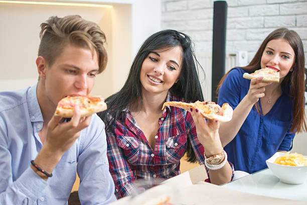 istock Smiling friends eating pizza at home. 598559488