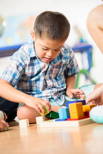 istock Young Hispanic boy with Down Syndrome plays with building blocks 598559982