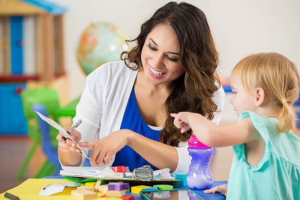istock Smiling teacher works with toddler on schoolwork in preschool 598560010