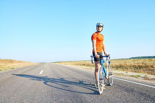 Young and ambitious triathlete standing with bike on open road