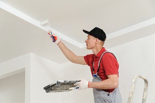 Painting the ceiling and walls. Painter uses paints roller.
