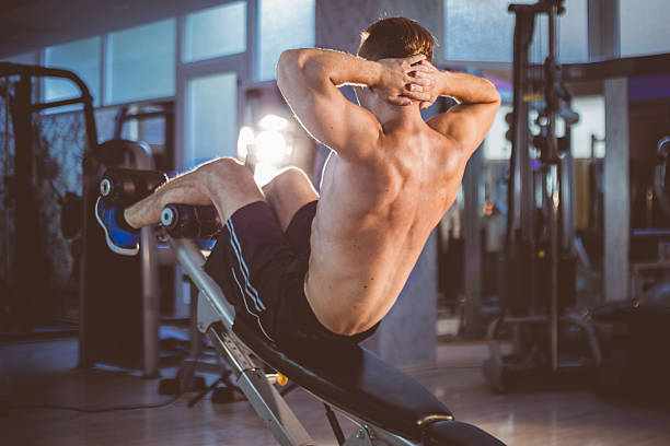 Incline sit-up training Young fitness man doing incline sit-up exersises deltoid photos stock pictures, royalty-free photos & images