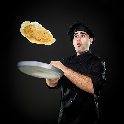 Chef showing his skill, flipping crepes pancake with a frying pan. About 30 years old, Caucasian male.