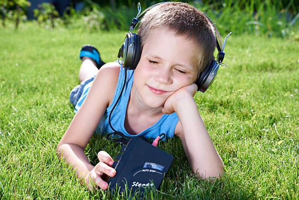 ragazzino sdraiato sull'erba con il vecchio lettore di audiocassette - one little boy audio foto e immagini stock