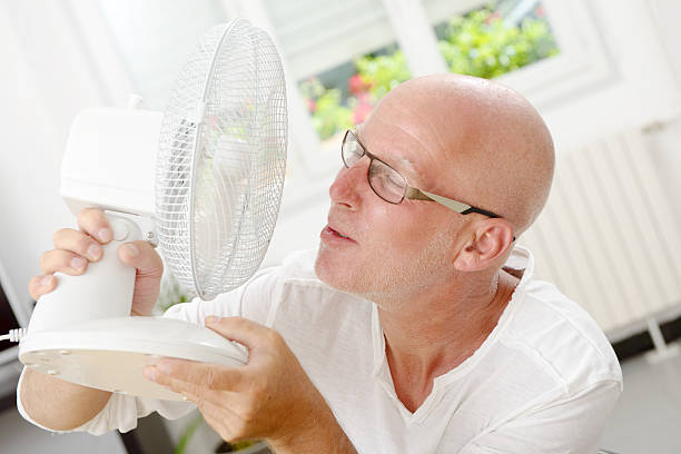 istock mature man refreshed with a fan 598673396