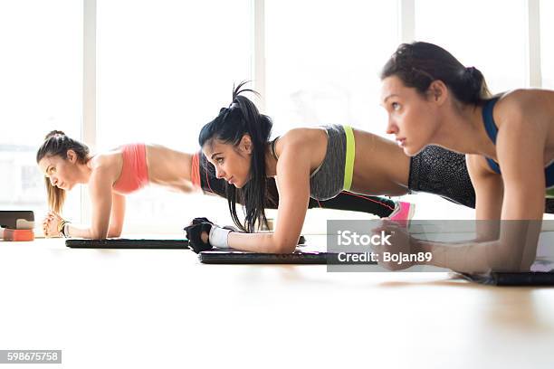 Three Attractive Sport Girls Doing Plank Exercise In Fitness Class Stock Photo - Download Image Now