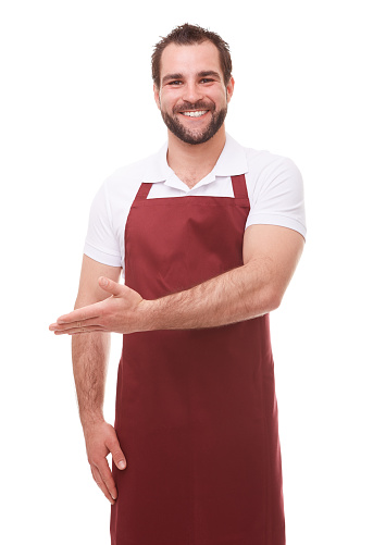 Happy man with red apron showing empty copyspace on white background