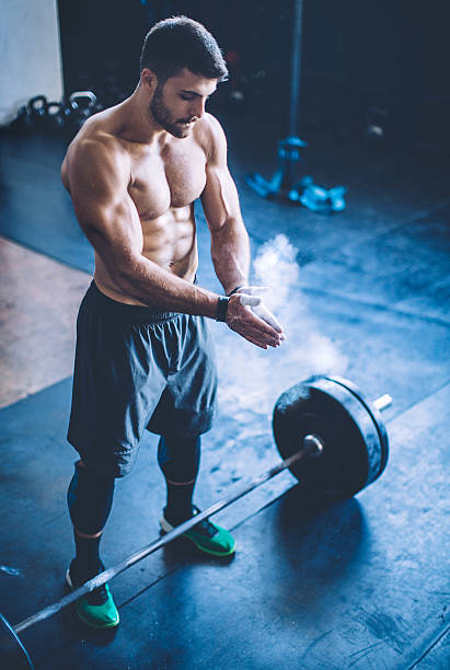 Let's get lifting! Young man exercising deadlift in gym. Professional sportists. Wearing sports clothing. crossfit chalk weightlifting weight training stock pictures, royalty-free photos & images